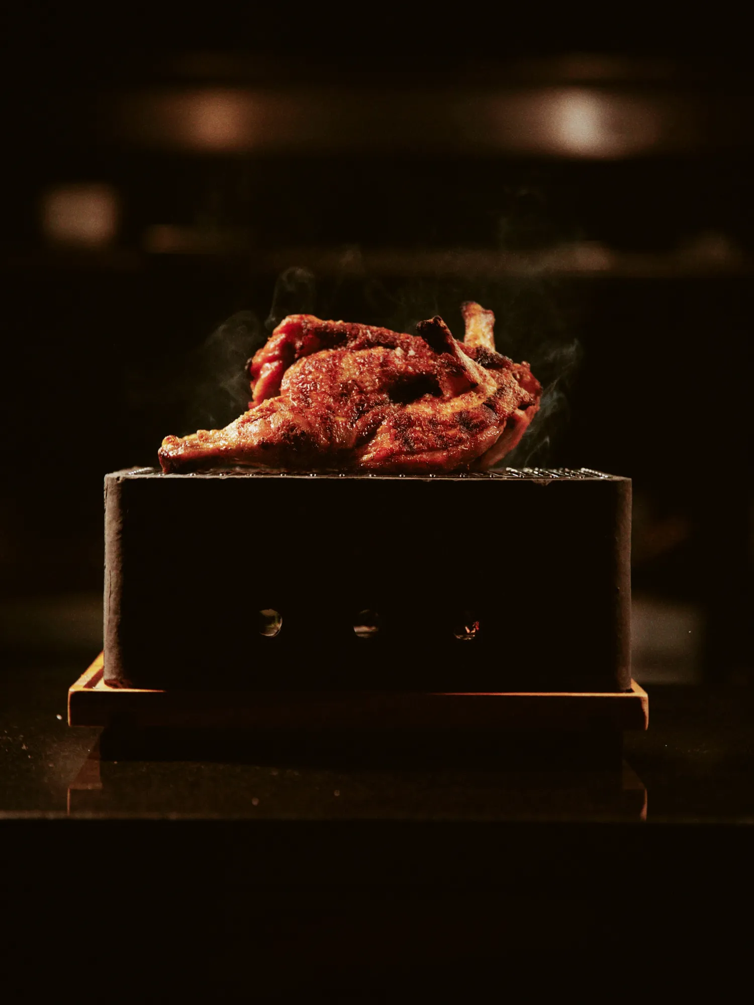 A roasted bird smoking on a dark stone box