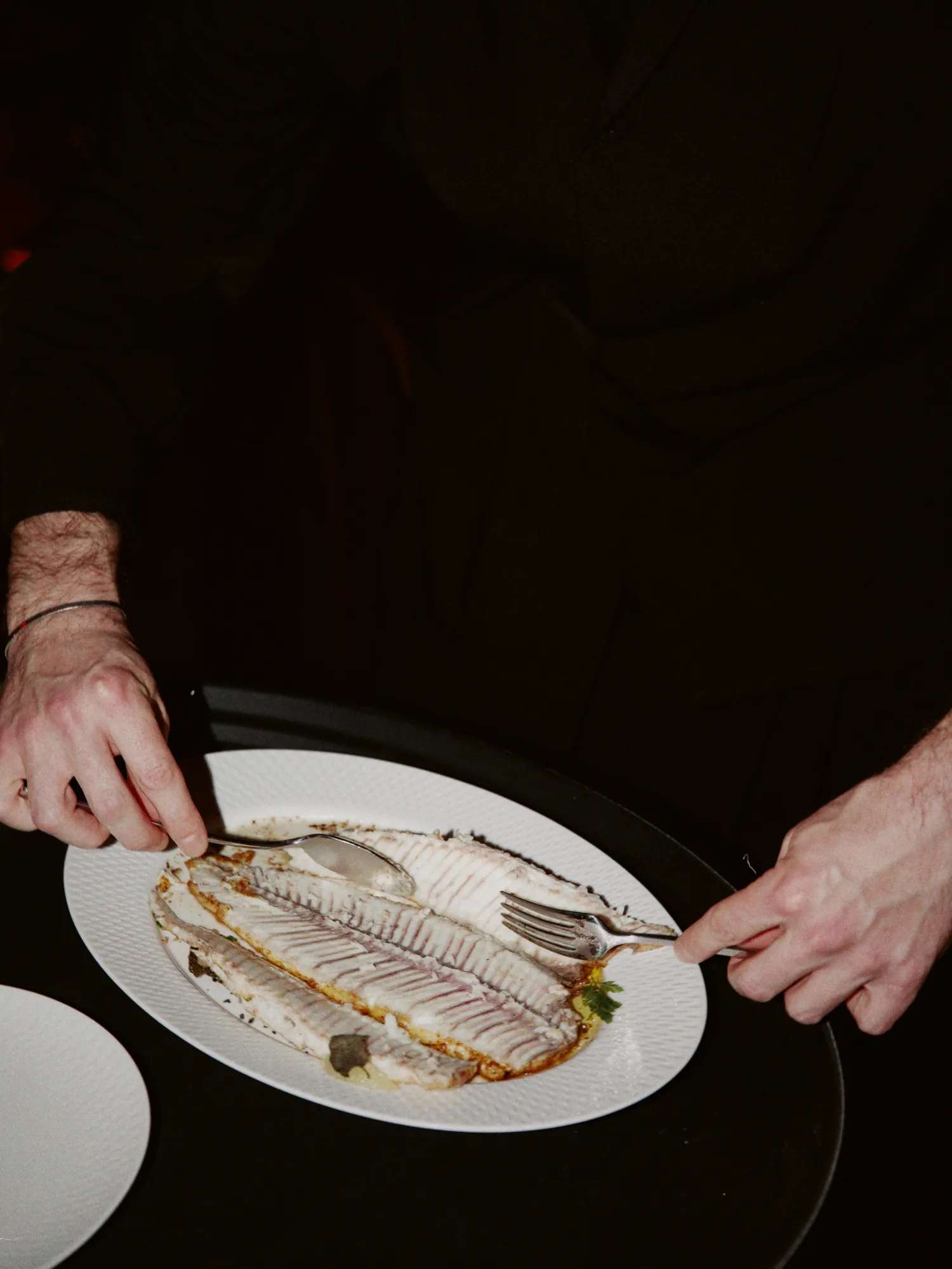 A whole fish being portioned onto a plate at the table