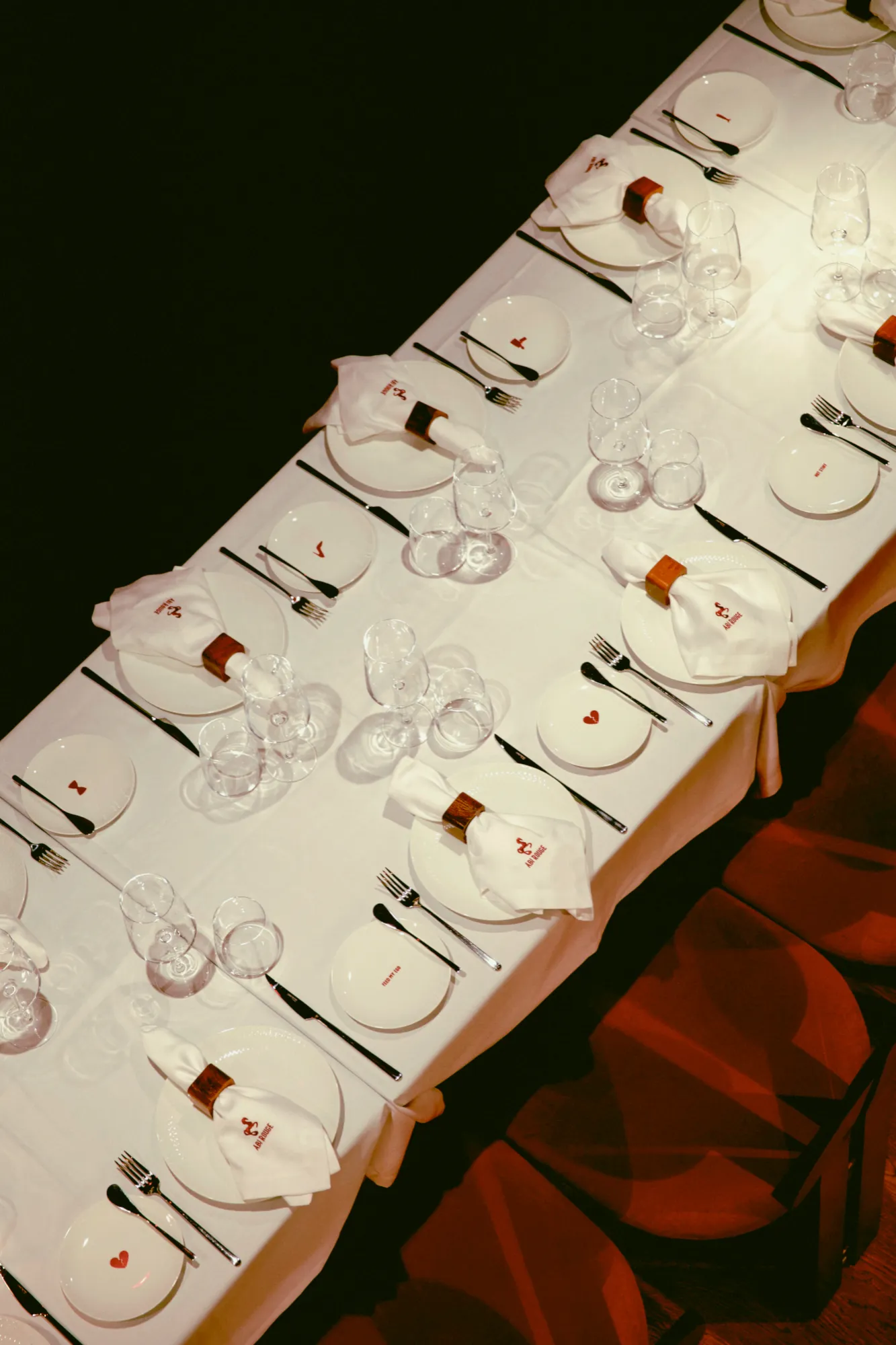 A long banquet table set with white linen, glassware, and napkins held by the red horse